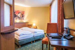 una camera d'albergo con due letti e una scrivania di Hotel Sperling mit E-Ladestation a Speyer
