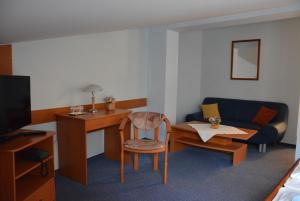 a room with a desk and a couch and a table at Hotel Vrsatec in Vršatské Podhradie