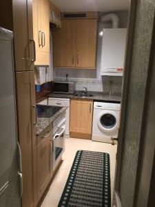 a kitchen with wooden cabinets and a washer and dryer at Living Gijon & Parking in Gijón +3 photos