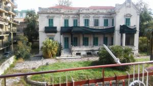 een oud huis met groene luiken op een gebouw bij B&B PinkHouse in Milazzo