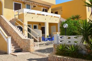 une maison avec des escaliers et des chaises en face de celle-ci dans l'établissement Residence Mare Blu, à Lampedusa