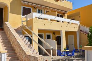 una casa con escaleras y sillas azules delante en Residence Mare Blu, en Lampedusa
