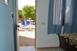 una puerta abierta a un patio con sillas y mesa en Residence Mare Blu, en Lampedusa