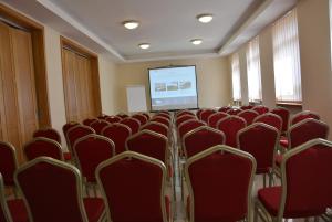Hotel Vrsatec في Vršatské Podhradie: قاعة اجتماعات مع كراسي حمراء وشاشة