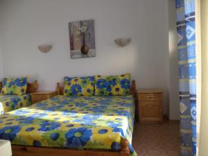 a bedroom with a bed with a yellow and blue comforter at Guest house Stoyanovi in Chernomorets