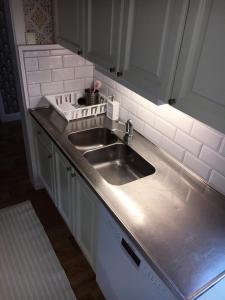 a kitchen with a stainless steel sink and white cabinets at Jaktlyckan, Tuna Gård in Tuna