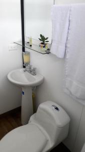 a white bathroom with a toilet and a sink at STAR HOTEL & CLUB DE TENIS, a 2 pasos del Aeropuerto JMC, Transporte Incluido in Rionegro