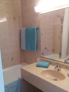 a bathroom with a sink and a tub and a mirror at Hôtel Les Palmiers in Bormes-les-Mimosas