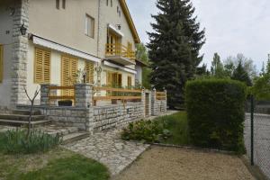 a house with yellow shutters and a fence at Soós Apartman in Balatonfüred