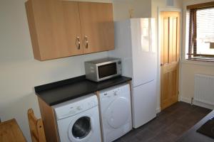 a kitchen with a washing machine and a microwave at Wick Apartment in Wick