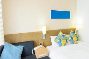 - une chambre d'hôtel avec 2 lits et des oreillers dans l'établissement Nishitetsu Resort Inn Naha, à Naha