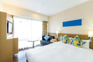 Habitación de hotel con cama y sofá en Nishitetsu Resort Inn Naha, en Naha