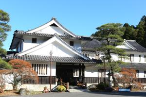 a large white building with a black roof at Iwamura Sanso -Castle Ryokan- in Ena