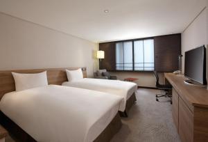 um quarto de hotel com duas camas e uma televisão em Royal Inn Taipei Nanxi - MRT Zhongshan Station em Taipei