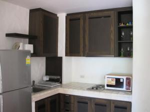 cocina con armarios de madera y microondas en Las Tortugas Apartment Unit C101, en Khao Tao