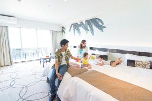 un grupo de personas sentadas en una cama en Kanehide Kise Beach Palace en Nago