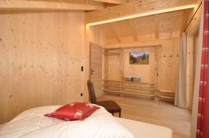 Schlafzimmer mit Holzwänden und einem Bett mit rotem Kissen in der Unterkunft Ferienhütten Lechtal Chalets in Elbigenalp