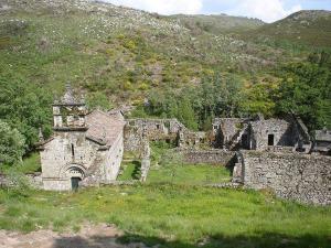 an old stone building in a field with a mountain at Cantinho Ti Carlos in Pitões das Júnias