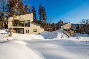 a house in the snow with a pile of snow at SOLAR CHALETS by Hakuba Hotel Group in Hakuba