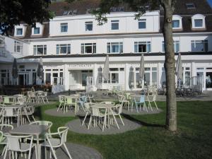 un groupe de tables et de chaises devant un bâtiment dans l'établissement Kurhaus Hotel, à Wyk auf Föhr