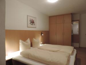 a bedroom with a large white bed and a cabinet at Apartments Alpenrose in Flirsch