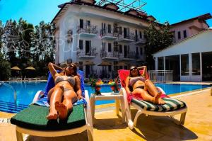 two women laying on lawn chairs next to a pool at Hotel Seril 2 in Fethiye