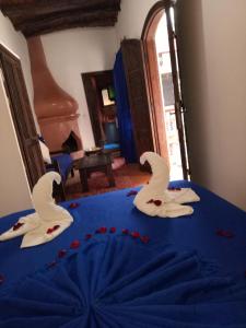 two white birds on a blue table with red flowers at Riad Chakir Mogador in Essaouira