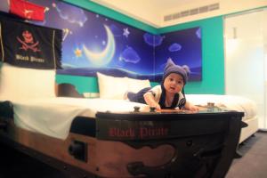 Una bambina giace in un letto con una valigia di Fairytale Yi Su Hotspring Hotel a Jiaoxi