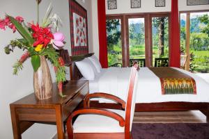ein Schlafzimmer mit einem Bett und einem Tisch mit einer Blumenvase in der Unterkunft Amartya Puri Green Cottages in Munduk