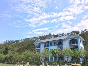 a blue house with a hill in the background at Magnni Villa in Nanzhuang