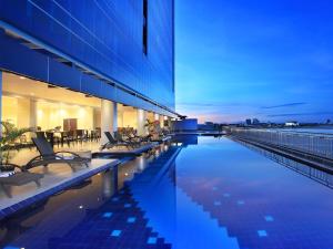 a building with a swimming pool with chairs next to it at Swiss-Belhotel Makassar in Makassar