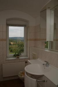 a bathroom with a white sink and a window at Ferienwohnung Lindemann in Weißig