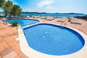 a swimming pool with lounge chairs and the water at Hotel Cala Fornells in Paguera