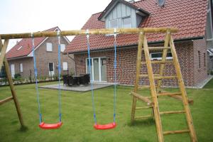 a swing set in a yard with a house at Ferienhaus Sophie in Thülsfeld
