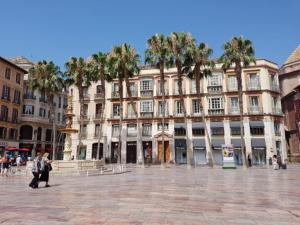 un grand bâtiment avec des palmiers devant lui dans l'établissement Piso Plaza de las Flores, à Malaga