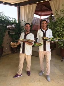two men holding two plates of food on trays at Riad Viva in Marrakesh