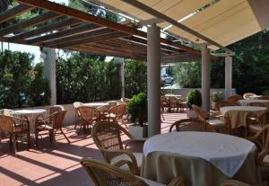 eine Außenterrasse mit Tischen, Stühlen, Tischen und einem Tischlesler in der Unterkunft Miami Hotel in Mati