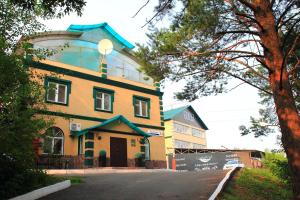 a large yellow building with a blue roof at Green Roof Hotel in Izhevsk