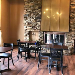 un restaurante con mesas y sillas de madera y una pared de piedra. en Soudersburg Inn & Suites Lancaster en Ronks