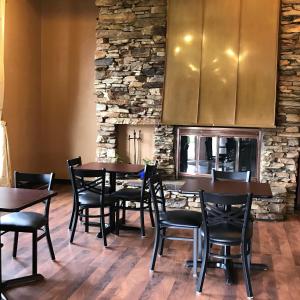 un restaurante con mesas y sillas de madera y una pared de piedra. en Soudersburg Inn & Suites Lancaster, en Ronks