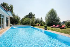 a swimming pool in a backyard with red chairs at Parkhotel Maximilian Ottobeuren in Ottobeuren