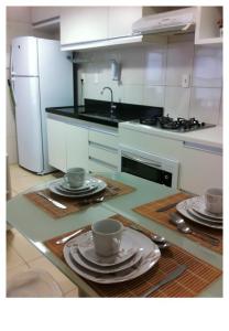 una cocina con platos y tazas en una mesa en Apartamento Orla do Cabo Branco, en João Pessoa