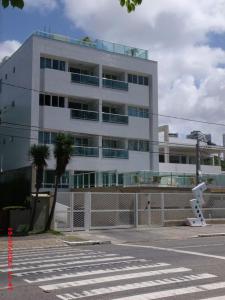 un gran edificio blanco con una palmera delante en Apartamento Orla do Cabo Branco, en João Pessoa