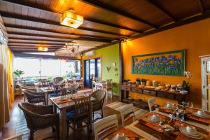 a restaurant with tables and chairs and a painting on the wall at Pousada DiMari in Boicucanga
