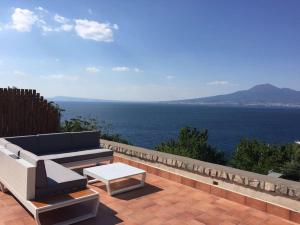 a patio with a couch and a table and the ocean at Villa Bikini on Sorrento Coast in Vico Equense