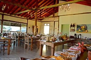a restaurant with wooden tables and chairs in a room at Penedo House Pousada in Penedo