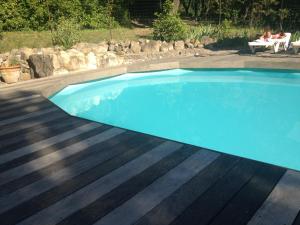 a blue swimming pool with a wooden deck at Au Fil de Soi in Vézénobres