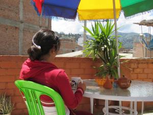 Ein junges Mädchen, das an einem Tisch unter einem Schirm sitzt. in der Unterkunft Casa de Ana B&B in Huaraz