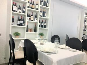 uma mesa branca com cadeiras pretas e garrafas de vinho em Las Cadenas em Ledesma