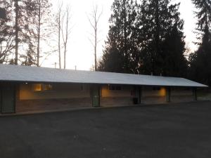 a building with a white roof in a parking lot at Monroe Motel in Monroe